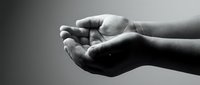 Open cupped hands in black and white showing gesture of receiving, giving or protection with dramatic lighting and shadow contrast for emotional concepts.