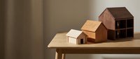 Wooden miniature house models on table showcasing architectural design concepts for home construction planning and real estate development projects.