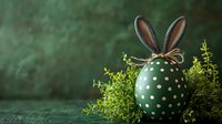 Green polka dot Easter egg decorated with bunny ears and twine bow, nestled in fresh spring greenery against dark emerald background. Holiday seasonal composition.