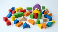 Colorful wooden building blocks scattered on white background featuring geometric shapes for educational play and creative construction activities.