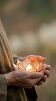 Hand holding glowing lotus flower lantern with warm light, symbolizing spirituality, hope, and mindfulness for wellness and meditation concepts.