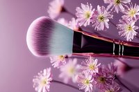 Makeup brush with soft pink bristles surrounded by delicate cherry blossoms on purple background, creating feminine beauty composition for cosmetic advertising.