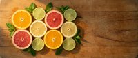 Fresh citrus fruits sliced in half arranged on wooden background with mint leaves for healthy eating and vitamin C nutrition concepts.