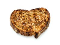 Toasted bread slice shaped like a heart with golden-brown surface and crispy texture, isolated on white background for bakery, food, and love-themed design projects.