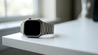 Modern silver smartwatch with metal band on white surface in minimalist interior setting for technology and lifestyle concepts.