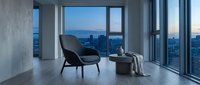 Modern minimalist interior with black lounge chair and side table overlooking city skyline at dusk from floor-to-ceiling windows, contemporary apartment design.
