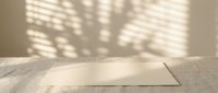 Blank white card on wooden surface with natural window light casting geometric shadows, suitable for mockups and design presentations.