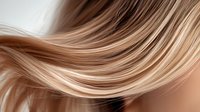 Smooth flowing blonde hair strands with gentle waves and highlights creating elegant motion effect against dark background, showcasing professional hair styling and beauty.