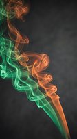Colorful smoke swirls in vibrant green and orange hues against dark background creating abstract flowing patterns for creative design projects.