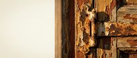 Rusty metal door latch on weathered wooden surface with peeling paint showing age and decay perfect for vintage restoration projects.