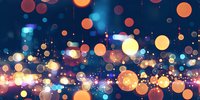 Glowing orange and blue bokeh lights creating magical atmosphere against dark background, abstract defocused circular light spots with sparkle effect.