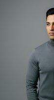 Young man with dark hair and olive complexion wearing gray turtleneck against neutral background. Suitable for business, fashion, lifestyle, and corporate marketing materials.