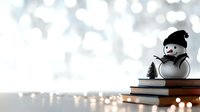 Cheerful snowman with black hat and scarf sitting on stack of books next to miniature pine tree against blurred bokeh winter background.