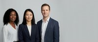 Professional diverse business team of three colleagues standing together in corporate attire against neutral background for workplace presentations.