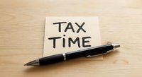Tax time reminder note with black pen on wooden desk for accounting and financial planning preparation.