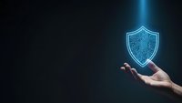Hand holding glowing digital shield with circuit pattern on dark background representing cybersecurity protection and data safety technology.