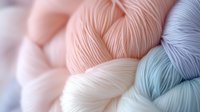 Soft pastel yarn skeins in pink, white and blue colors arranged together, perfect for knitting, crocheting and textile crafts projects.