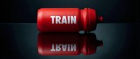 Red cylindrical tank or container with white "TRAIN" text displayed on its surface, positioned on a reflective dark background, suitable for industrial, transportation, logistics, and design projects.