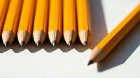 Yellow pencils with sharpened tips arranged in a row on white background, one pencil separated to the side, casting shadows, suitable for education, writing, art, and creativity concepts.