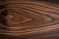 Natural brown wood grain texture with swirling patterns and dark streaks showing detailed surface of exotic hardwood material for furniture and interior design.