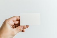 Hand holding blank white square card against neutral background, ready for custom text or branding design on business cards, invitations, or marketing materials.