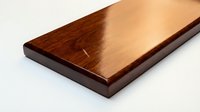 Polished mahogany wood plank with rich grain pattern and glossy finish on white background, perfect for carpentry and woodworking projects.