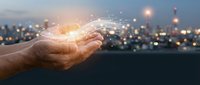 Cupped hands holding glowing digital network connections with light particles against blurred city skyline at dusk for technology and innovation concepts.