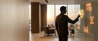 Businessman in dark suit interacting with glowing digital interface displaying analytics charts and graphs in modern office space with warm lighting.