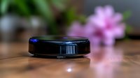 Robotic vacuum cleaner on wooden floor with soft pink flower bokeh in background, modern smart home cleaning technology in action.