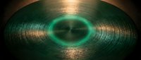 Vinyl record with glowing neon green center label and metallic grooves, isolated on dark background for music, retro, and design projects.