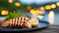 Grilled lobster tail with lemon on dark plate against blurred bokeh lights background, close up view of luxury seafood dinner served at restaurant.