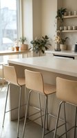 Modern kitchen island with light wood bar stools, white countertop, and potted plants on shelves near window for contemporary home interior design and lifestyle.
