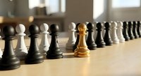 Golden chess pawn standing out among black and white pieces on wooden board, symbolizing leadership, uniqueness and strategic thinking in business.