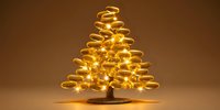 Glowing spiral Christmas tree made of golden light trails against warm brown background, creating festive holiday atmosphere.