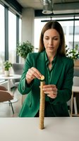 Professional businesswoman in green suit stacking golden coins at modern office desk, representing financial growth, investment planning and wealth building.