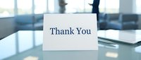 Thank You card standing on office desk with blurred business background, expressing gratitude and appreciation in professional setting.