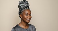Mature African American woman with gray braided updo hairstyle wearing dark shirt against neutral background, representing aging, natural beauty, and professional portrait use.