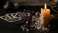 Mystical altar setup with burning candles, tarot cards, crystals, pentagram symbol, and dried lavender for spiritual rituals and divination practices.