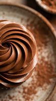 Rich chocolate buttercream frosting swirl on rustic ceramic plate with cocoa powder dusting for bakery dessert and confectionery culinary photography.