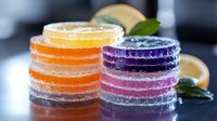 Colorful fruit jelly candies stacked in towers with sugar coating on dark surface. Sweet confectionery treats in vibrant rainbow colors for dessert concepts.