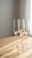 Three empty champagne flutes arranged on wooden table with soft natural lighting creating elegant shadows for celebration and dining concepts.