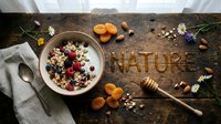 Granola bowl with fresh berries, dried apricots, nuts, honey dipper, and wildflowers on rustic wood with Nature lettering.