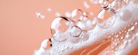 Delicate soap bubbles on soft peach background create dreamy macro composition with reflective surfaces and transparent spheres in gentle morning light.