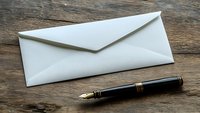 White paper envelope and luxury fountain pen on rustic wooden table background, minimalist business correspondence composition for office and mail.