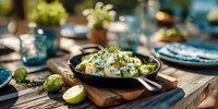Creamy risotto with herbs served in cast iron pan on wooden board, garnished with lime slices for elegant outdoor dining experience.