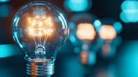 Glowing light bulb with illuminated filament on blurred turquoise background, creative innovation concept for business solutions and bright ideas.