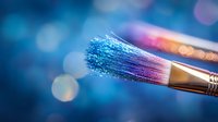 Paint brush with blue and purple paint residue against blurred bokeh background creates magical artistic atmosphere for creative design projects.