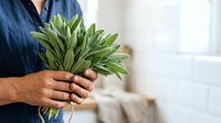 Man holding fresh green leafy vegetables indoors, promoting healthy eating and organic produce for culinary and wellness content.
