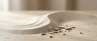 Scattered wooden blocks and tiles on sand surface with curved ceramic dish, depicting construction, design, or architectural planning concept.