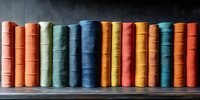Colorful vintage books arranged in row on dark wooden shelf, spines showing vibrant shades of orange, blue, green and red creating rainbow pattern. Library concept.
